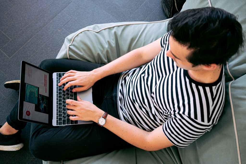 A man using his laptop while sitting on his couch relaxing and browsing the Internet